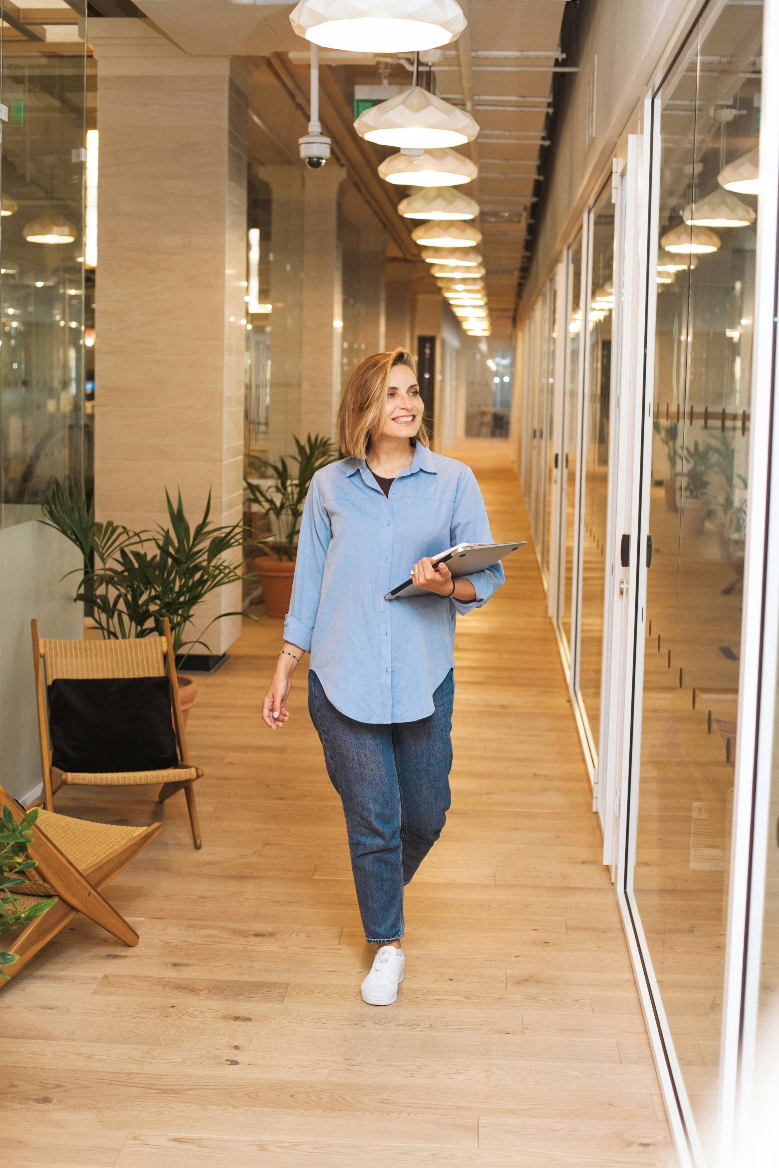 A professional walking through an office, laptop in hand, mid-transition
